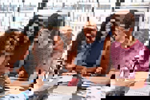 group of high school sophomores sitting at a table reading