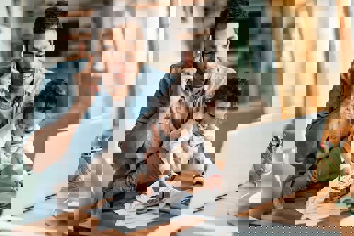 Dad using laptop while talking on mobile and holding curious toddler